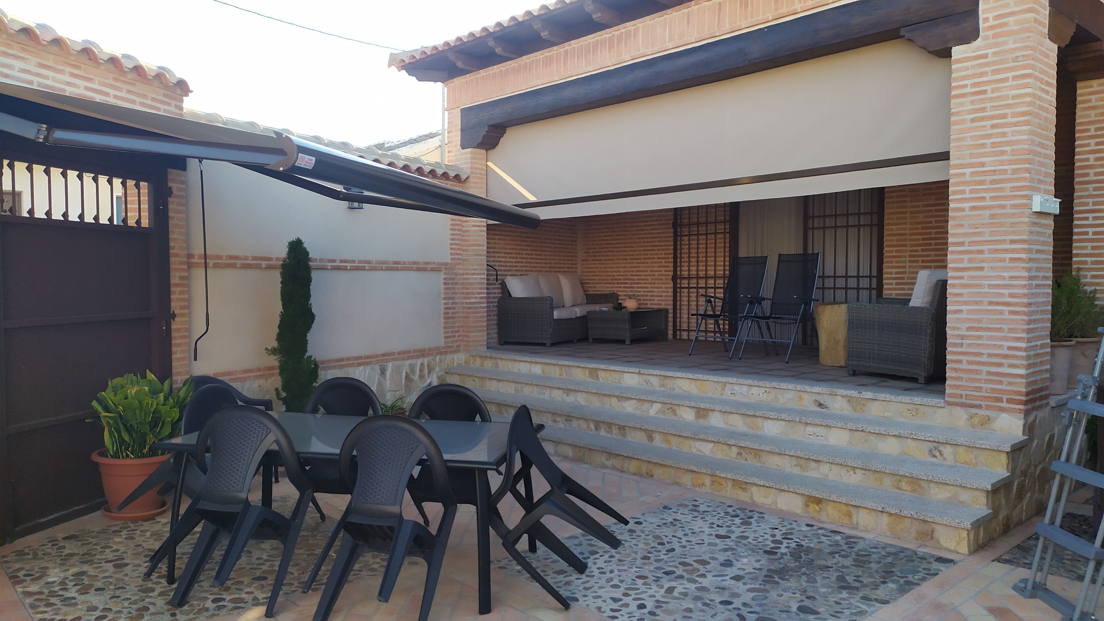Un patio al aire libre con una mesa de comedor y sillas, un sofá y una pequeña mesa con sillas.