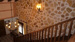 A stone wall with a chandelier and wooden staircase. - Two steps from Toledo and Las Barrancas de Burujón (Escalonilla)