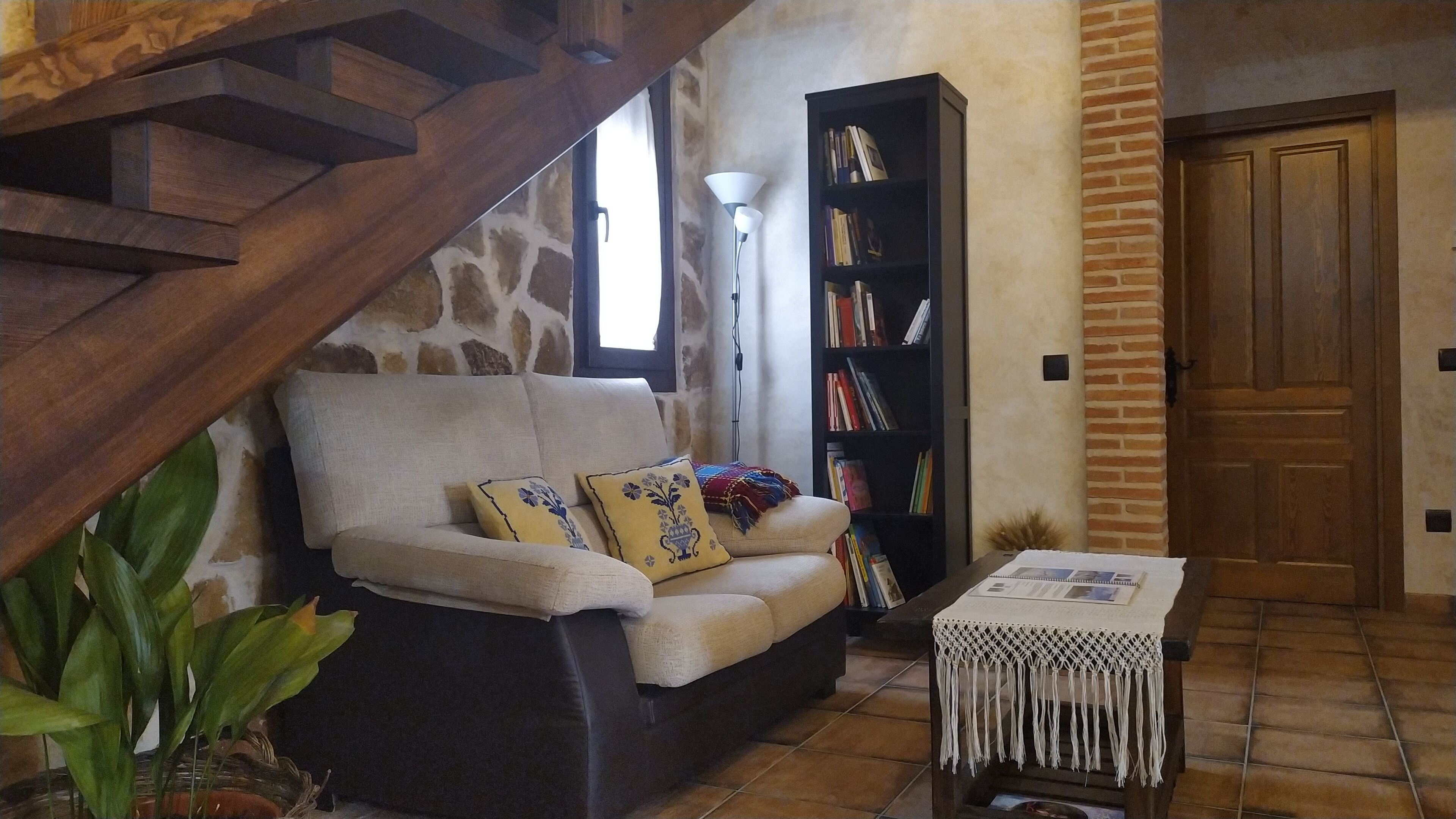 Una sala de estar acogedora con un sofá, una estantería, una mesa de centro y una escalera.