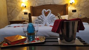 A hotel room with a bed, two wall-mounted lamps, a minibar, a tray with a bottle, glasses, and a red towel. - Two steps from Toledo and Las Barrancas de Burujón (Escalonilla)