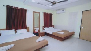 A hotel room with two beds, red curtains, a ceiling fan, and an air conditioning unit. - Rajhuns Deluxe Lodging (Kolhapur)
