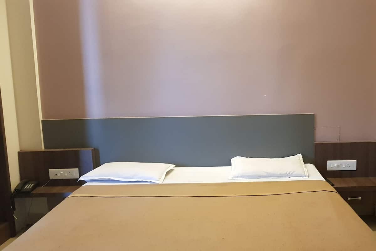 Ein Hotelzimmer mit einem Bett, zwei Nachttischen und einem an der Wand befestigten Telefon.