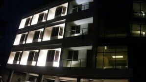 A multi-story building with illuminated windows and balconies, suggesting a residential or hotel structure. - Hotel Bhagwati Lodging (Kolhapur)