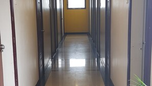 A long, narrow hallway with doors on both sides, a tiled floor, and a ceiling light. - Hotel Bhagwati Lodging (Kolhapur)