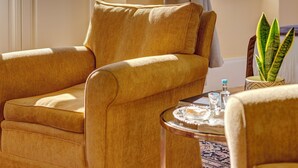 A room with two armchairs, a small round table with a tray, and a potted plant. - Palazzo Santa Maria - Historic Hotels of Europe (Syros)