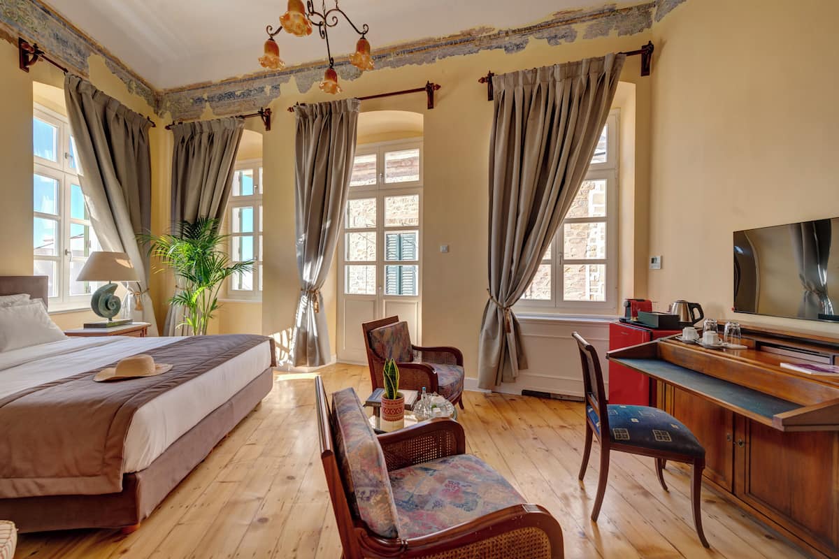 A hotel room with a bed, a desk, a chair, a television, and a window with curtains.