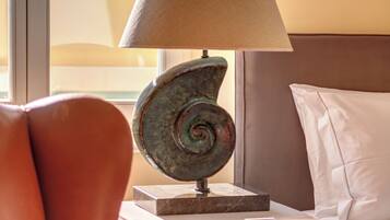 A bedroom with a bed, a lamp, a chair, and a nightstand.