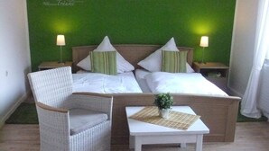 Een slaapkamer met een bed, twee nachtkastjes, een stoel en een tafeltje met een plant.