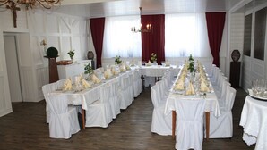 Een statige eetzaal met lange tafels gedekt voor een maaltijd, witte tafelkleden en elegante serviesopstellingen.