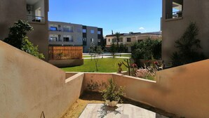 A courtyard with a tiled floor, a wooden fence, and potted plants. - Superbe appartement avec Piscine (La Soukra)
