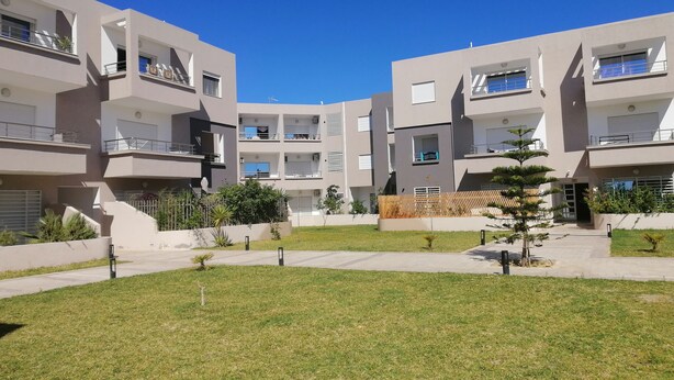 A modern apartment complex with multiple balconies, a central courtyard, and a well-maintained lawn. - Superbe appartement avec Piscine (La Soukra)