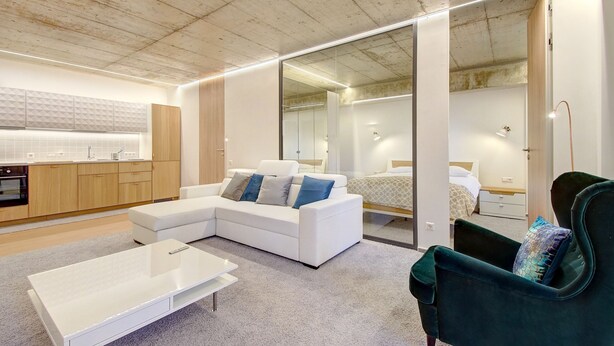 A modern apartment with a kitchen, a living area with a white sofa and a green armchair, and a bedroom with a bed and nightstand. - Kauno-Algirdo Luxury Vilnius Apartments (Vilnius)