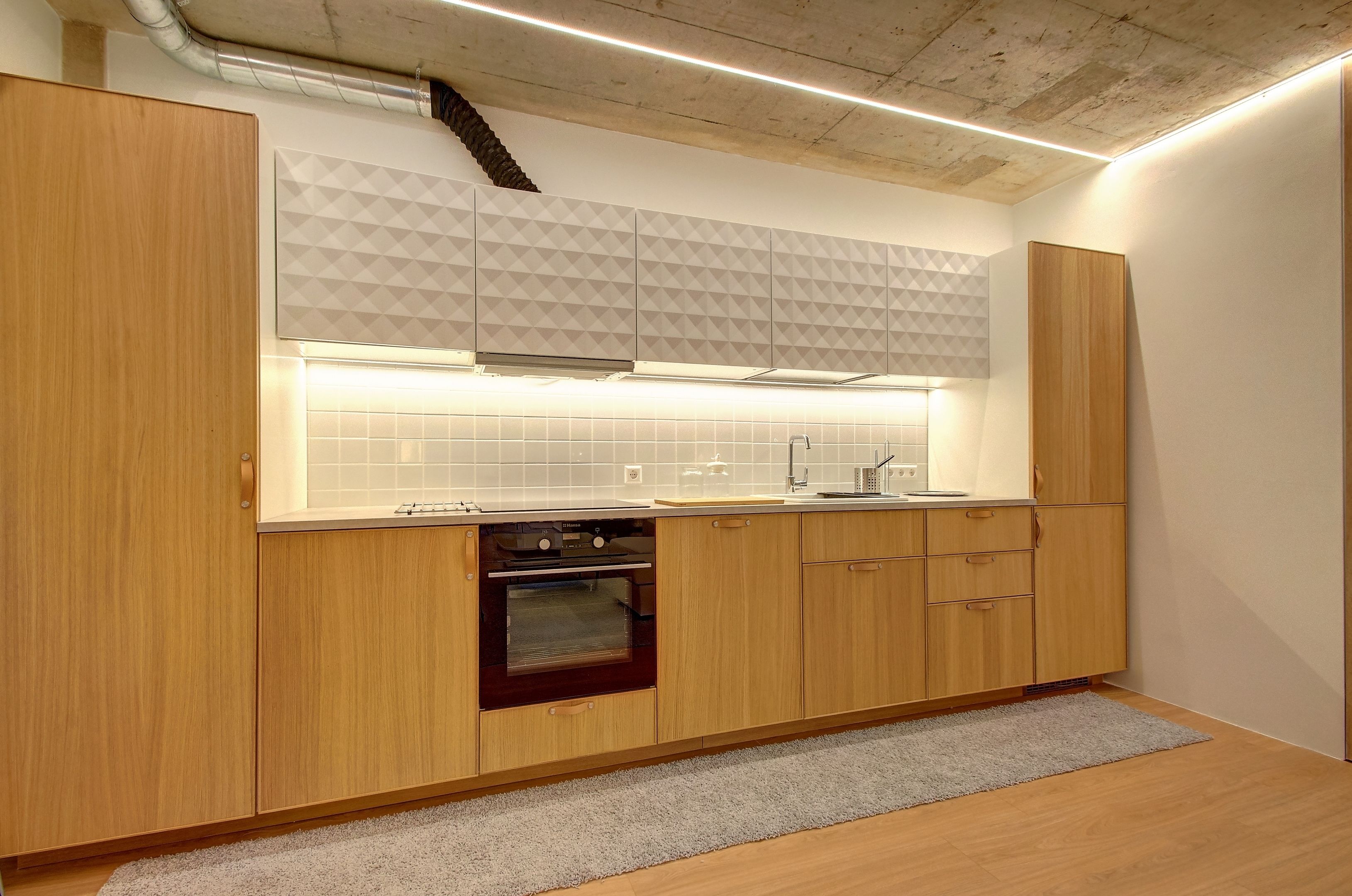 Una cocina moderna con armarios de madera, horno empotrado y salpicadero geométrico.