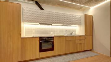 Una cocina moderna con armarios de madera, horno empotrado y salpicadero geométrico.
