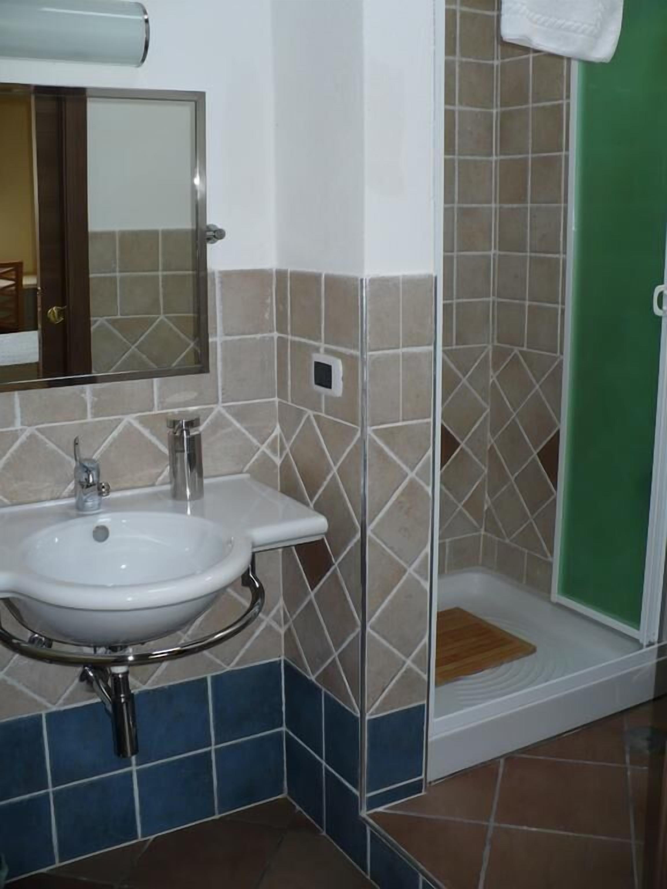 Een badkamer met een wastafel, spiegel en douche.