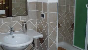 Een badkamer met een wastafel, spiegel en douche.