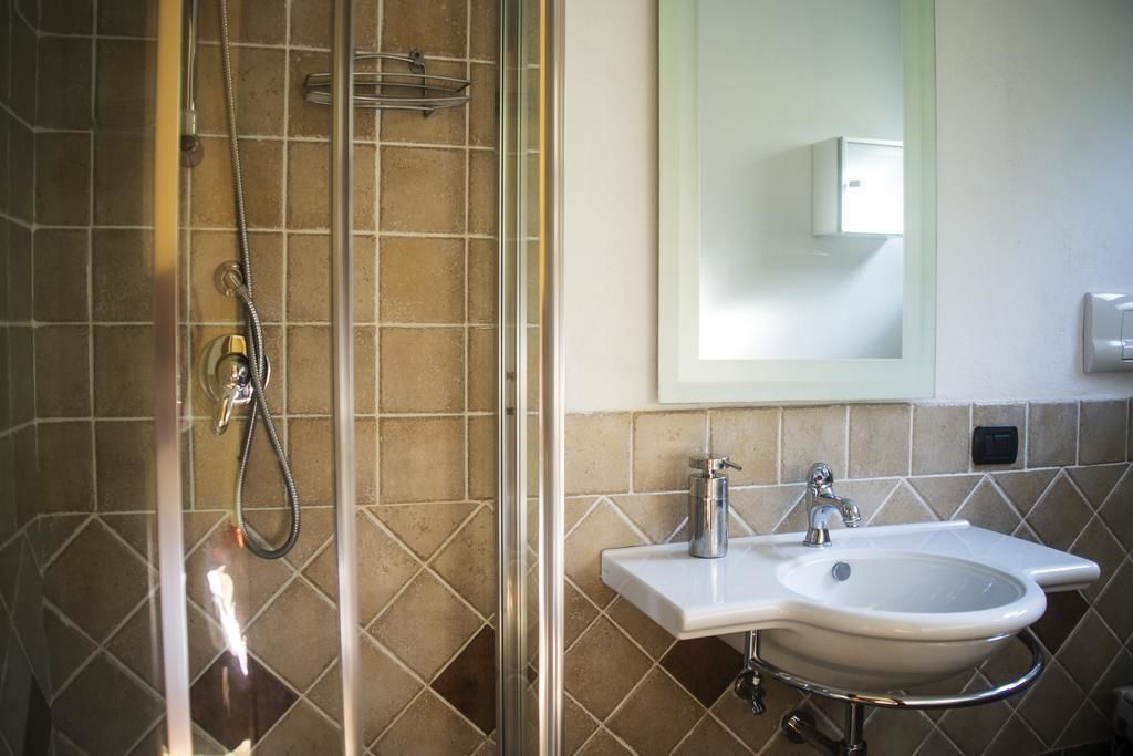 Een badkamer met een douchecabine van glas, een wit wastafelmeubel met een chromen kraan en een spiegel erboven.