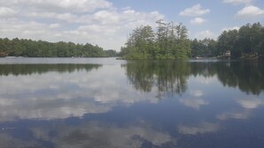 Un lago tranquilo cuyo reflejo muestra el cielo y los árboles.