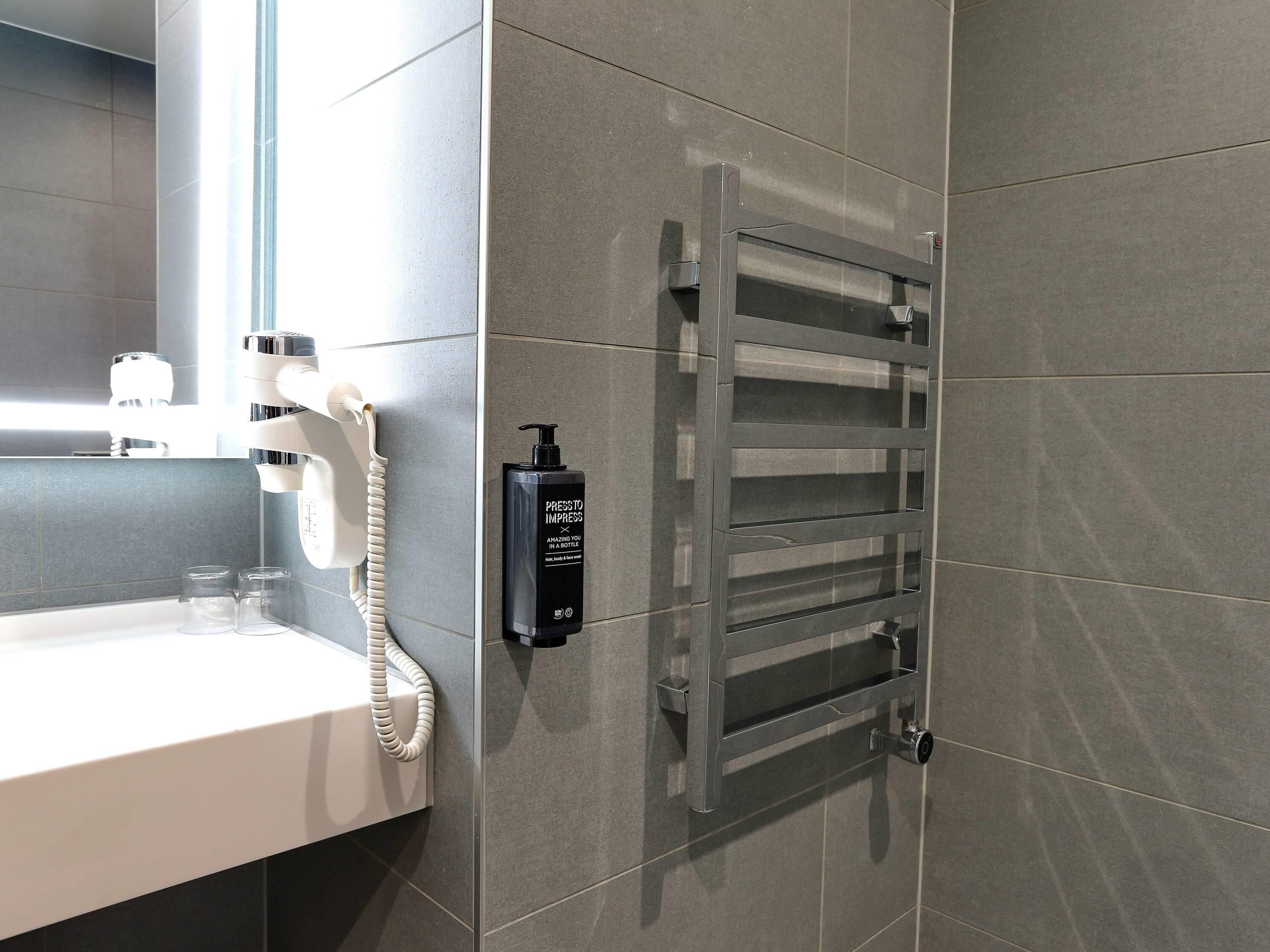 Un baño moderno con un lavabo blanco, un teléfono integrado y un perchero para toallas.