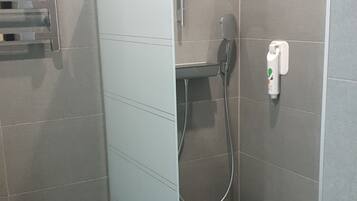 Une petite salle de bain moderne avec une douche à parois de verre, des toilettes et un porte-serviettes.