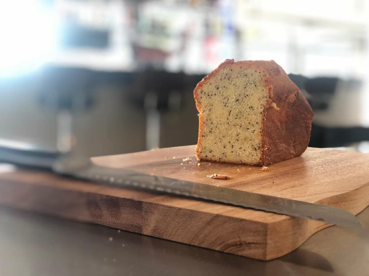 A loaf of bread on a wooden cutting board with a knife beside it.