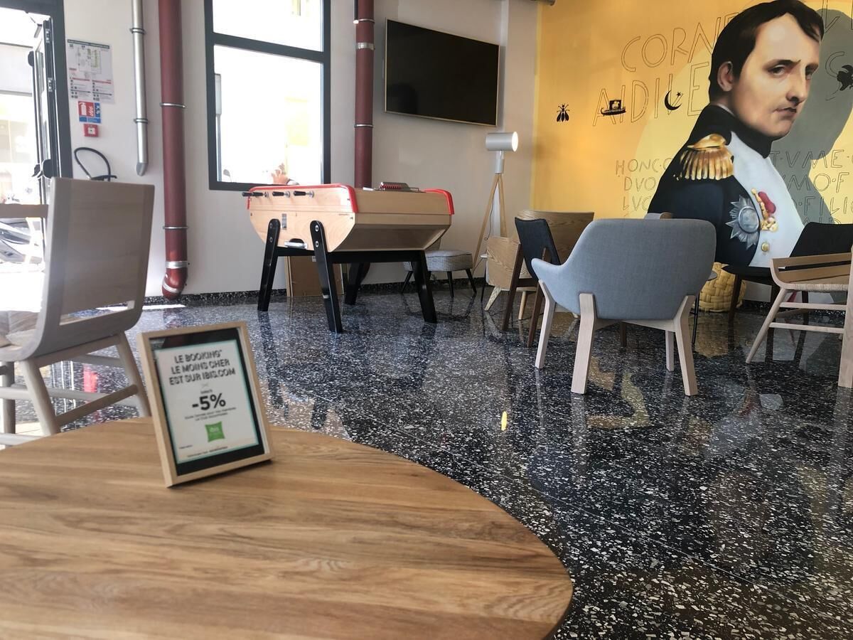 Un intérieur moderne avec une table en bois, des chaises, un sol noir à motifs et une affiche accrochée au mur.