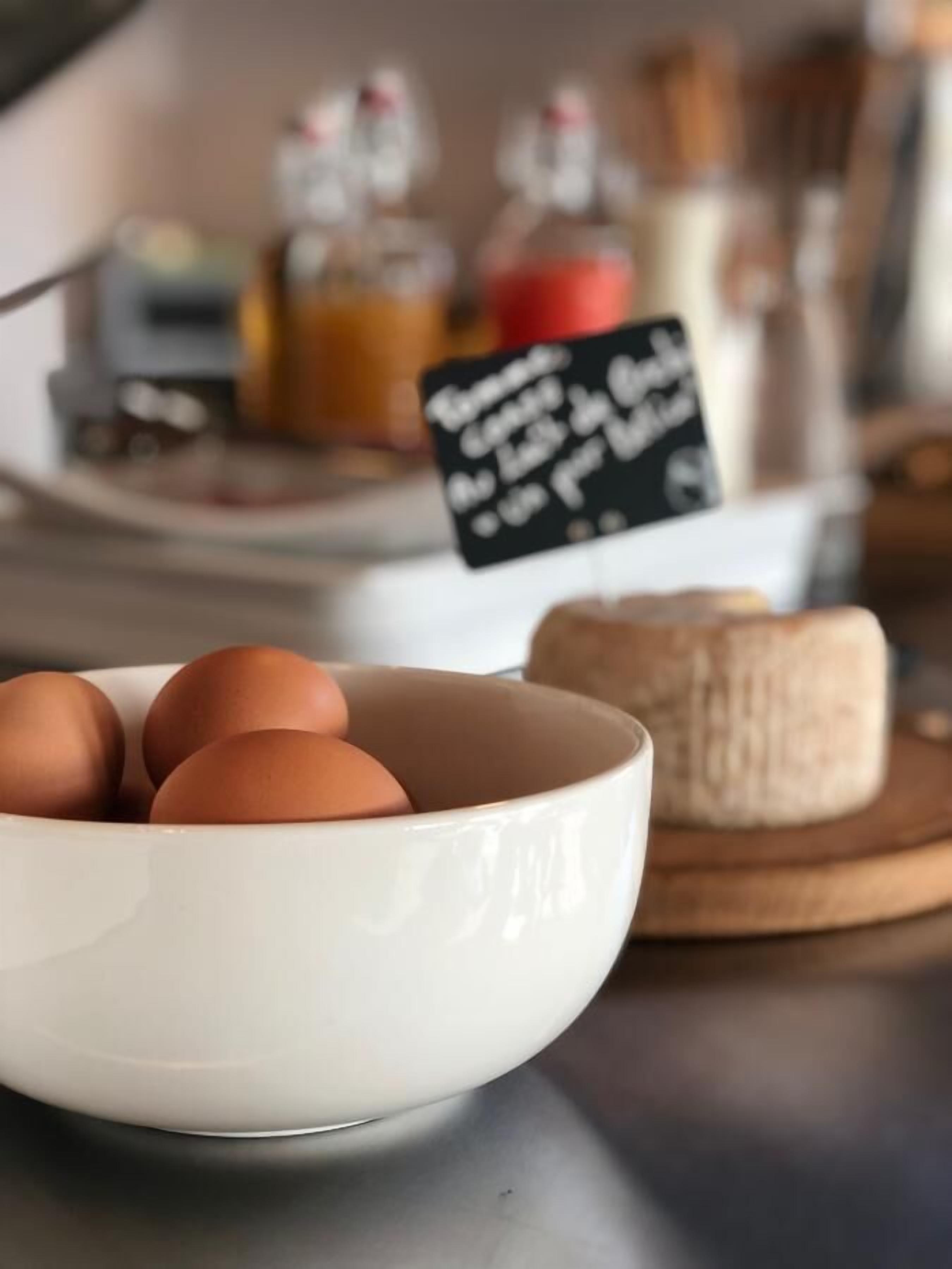 A white bowl with brown eggs on a countertop.