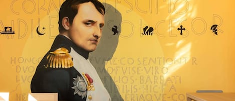 A room with a mural of a historical figure, a wooden table, and a bench.