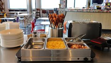 Un buffet avec des plateaux de macaronis au fromage, de bacon et d’autres plats.