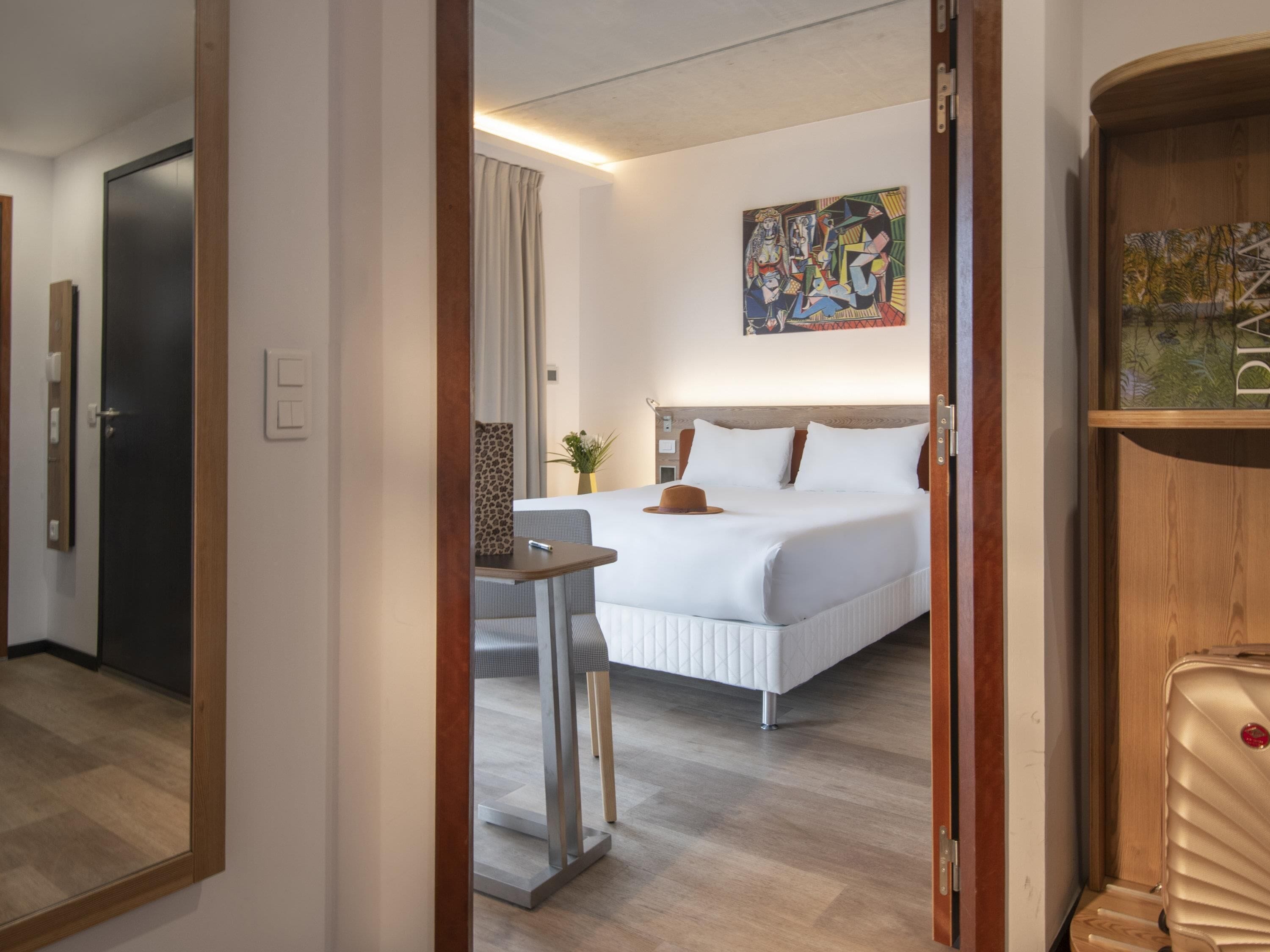Une chambre d’hôtel avec un lit, une table de chevet et un tableau au mur.