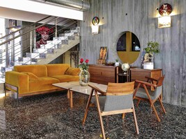 Una sala de estar moderna con un sofá, una mesa de centro y un comedor con sillas y un aparador de madera.