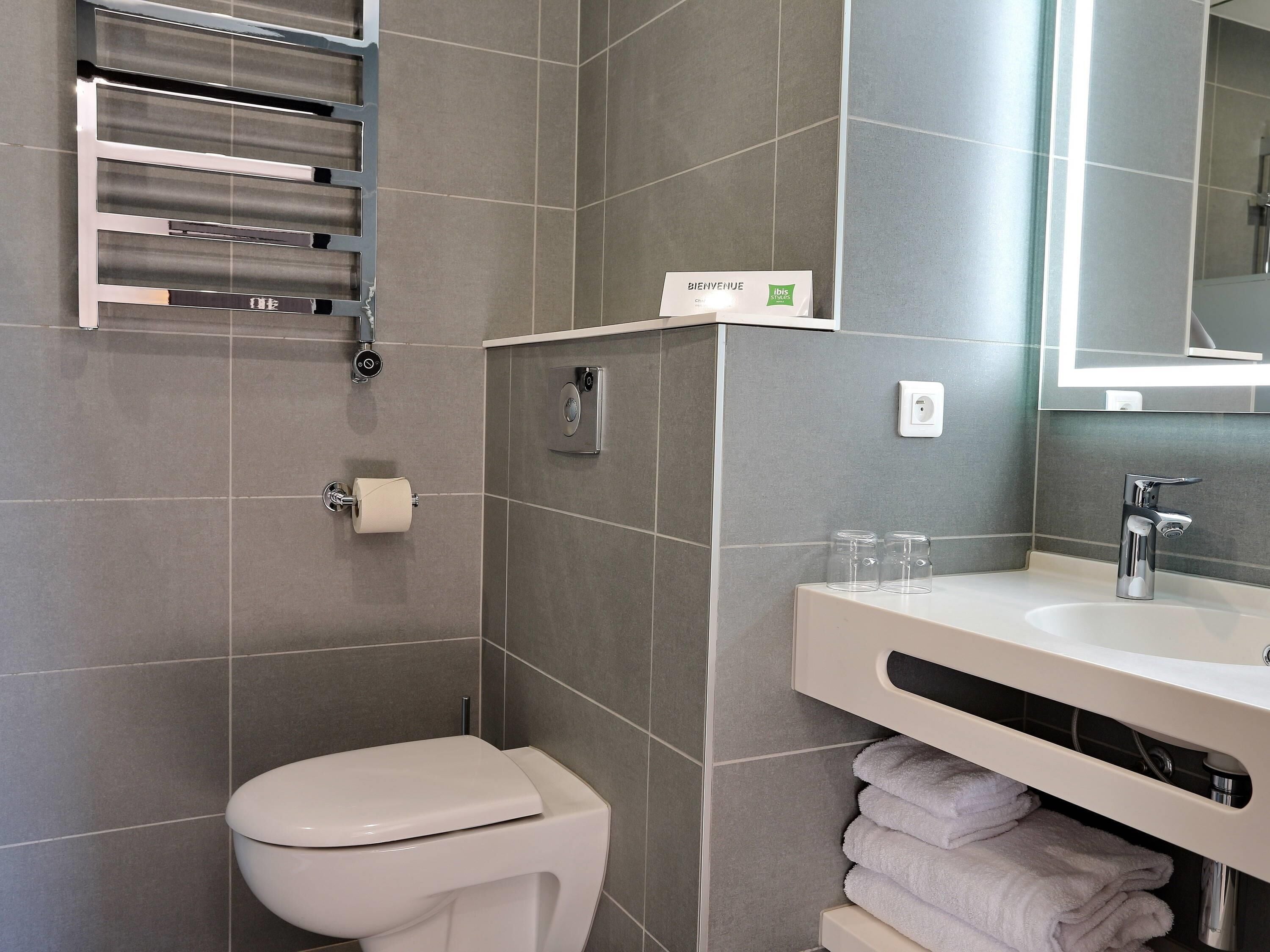 Un baño moderno con inodoro, lavamanos y un perchero para toallas.