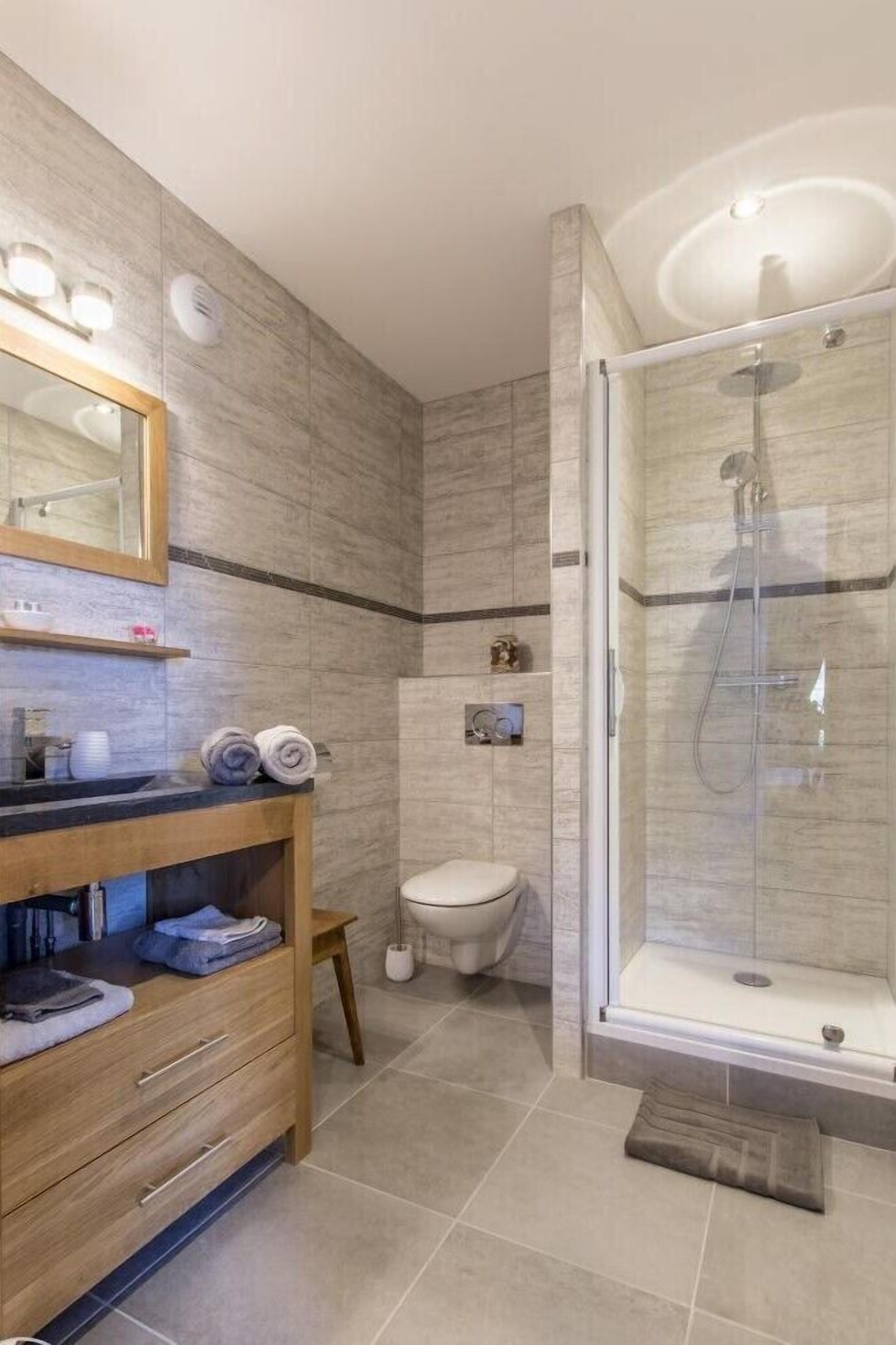 Un baño moderno con tocador de madera, cabina de ducha de vidrio y un inodoro.