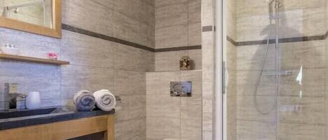 Un baño moderno con tocador de madera, cabina de ducha de vidrio y un inodoro.