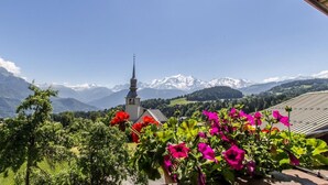 Una iglesia con campanario, rodeada de montañas y flores.
