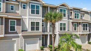 A multi-story residential building with a symmetrical facade, multiple garage doors, and a central palm tree.