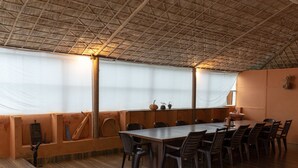 Un restaurante con techo de paja alto, mesas y sillas de madera.