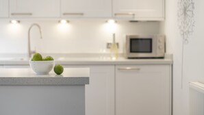 A modern kitchen with white cabinets, a microwave, and a bowl of limes on the counter.