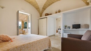 A bedroom with a bed, a brown sofa, a TV, and a white wardrobe. - Villetta Evelyn (Montesano Salentino)