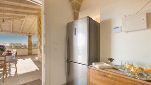 A kitchen with a stainless steel refrigerator, wooden cabinets, and a dining area with a table and chairs. - Villetta Evelyn (Montesano Salentino)