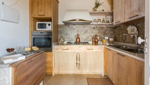 A compact kitchen with wooden cabinets, a microwave, oven, and a gas stove. - Villetta Evelyn (Montesano Salentino)