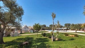 A well-maintained outdoor area with a swimming pool, lounge chairs, and a stone building. - Trulli di Buontempo (Francavilla Fontana)