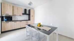 Eine moderne Küche mit Holzausstattung, einer schwarzen Arbeitsplatte und einem Essbereich mit Tisch und Stühlen.