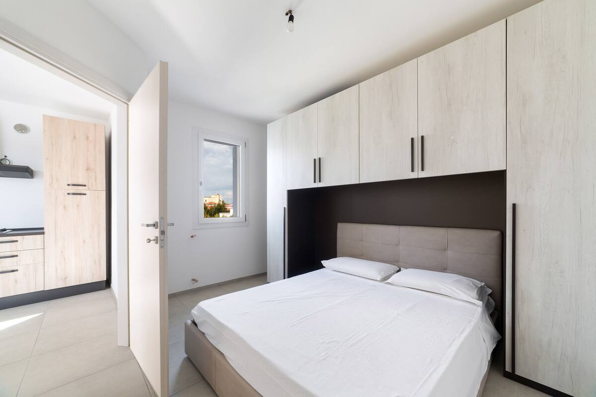 Quarto com cama, guarda-roupa e janela.