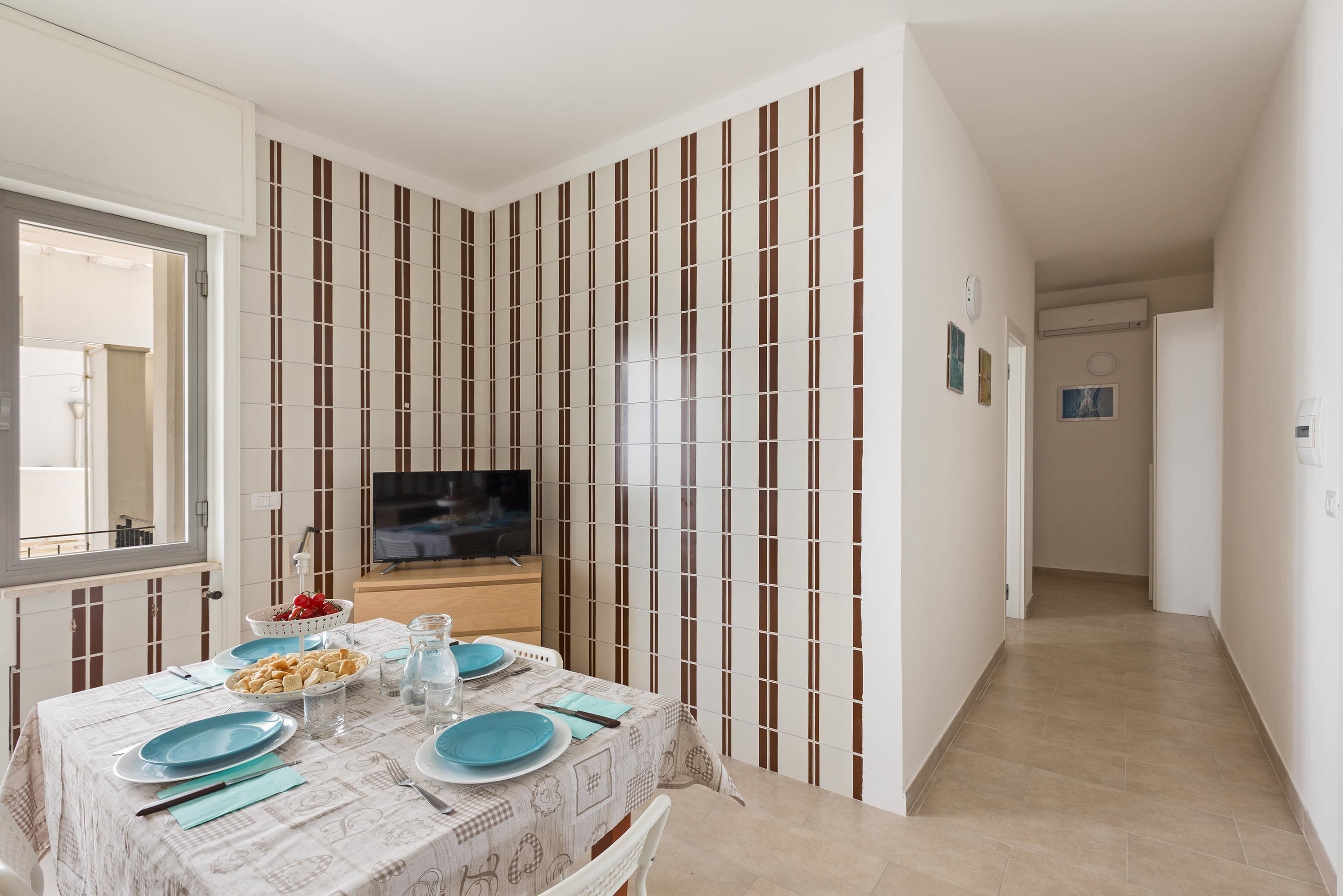 A dining area with a table set for four, a TV, and a striped wall.
