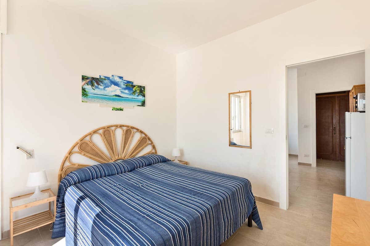 Une chambre à coucher avec un lit, une table de chevet, une lampe, un tableau et un miroir.