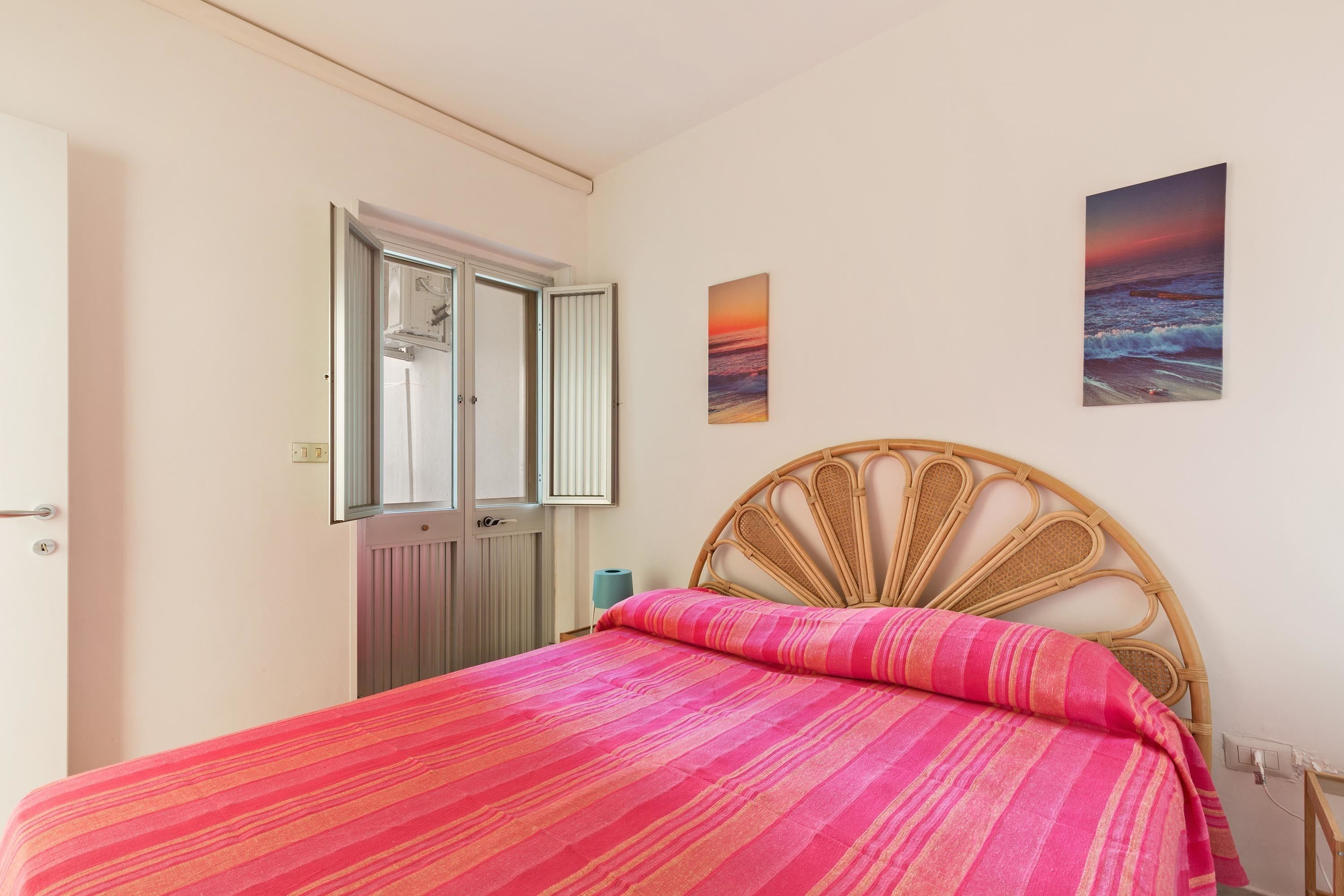 A bedroom with a bed, a window, and a wall-mounted picture.