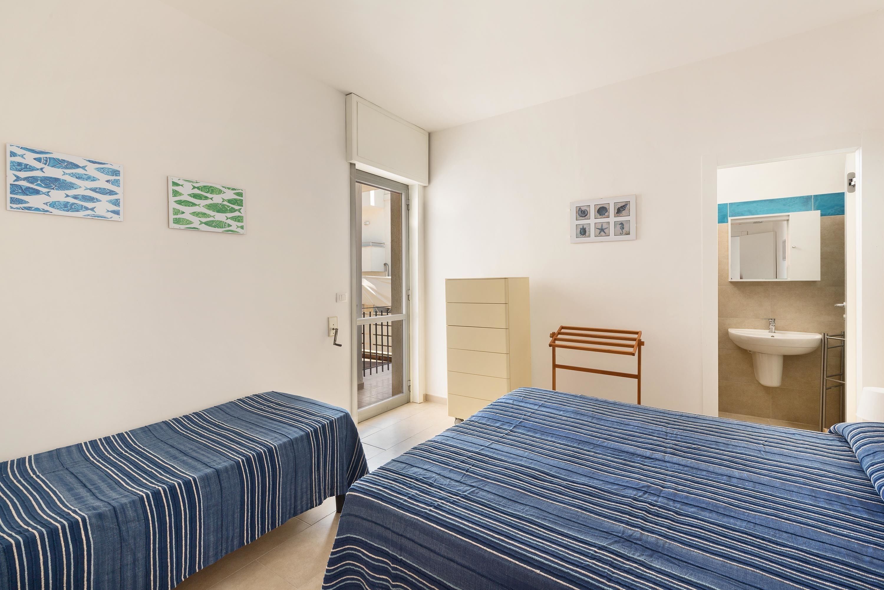 Une chambre avec deux lits, une fenêtre, une porte, un lavabo et un miroir.