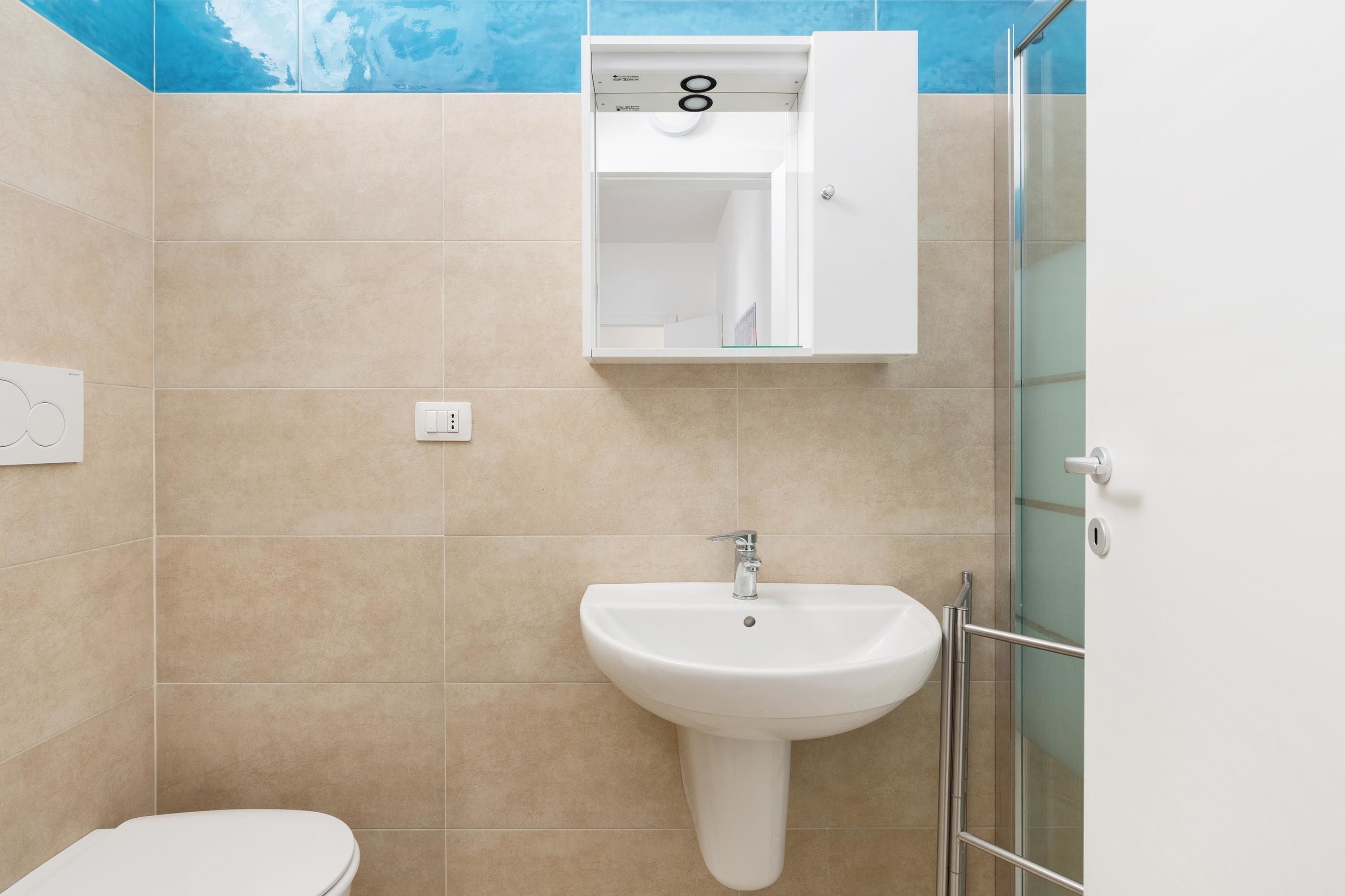 A bathroom with a white sink, a toilet, and a glass shower enclosure.