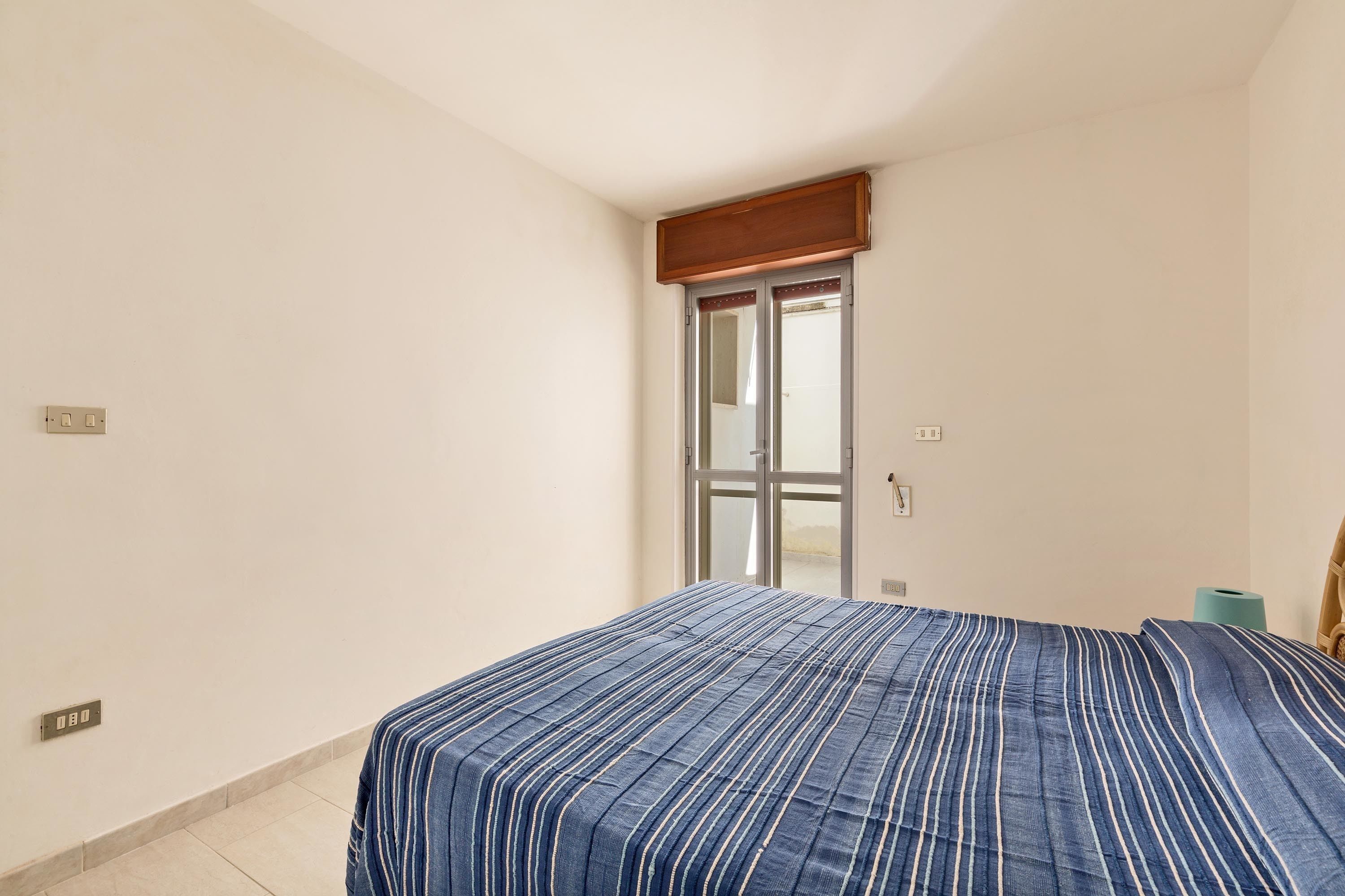 Un dormitorio con cama, ventana y puerta.
